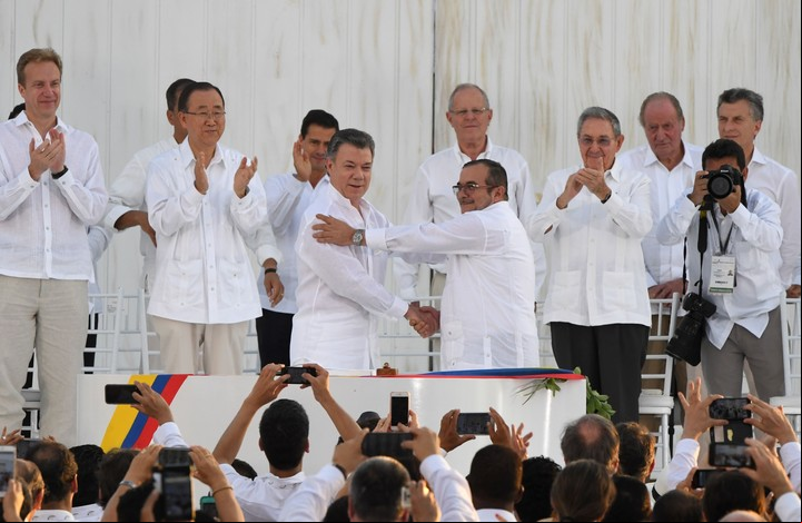 El presidente de Colombia Juan Manuel Santos y el lider de las FARC, Rodrigo Londoño, estrechan sus manos tras firmar el acuerdo de paz en Cartagena ante líderes mundiales. (AFP)