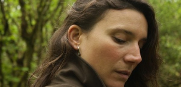 Claire-Louise Bennett tirada en el pasto, leyendo