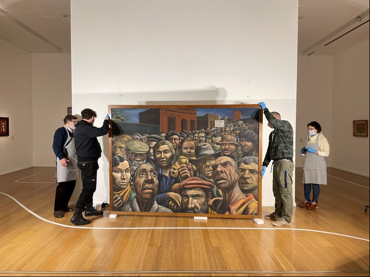 Personal manipula una de las obras emblemáticas de la colección, “La manifestación”, de Berni.