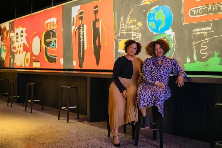 De izquierda a derecha, Lisane Basquiat y Jeanine Heriveaux, hermanas del artista, curadoras de la muestra. Detrás de ellos está el “Nu Nile” de su hermano de 1985. Crédito Flo Ngala para The New York Times