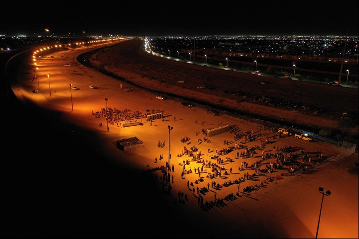 Migrantes esperan de noche junto al muro fronterizo para entregarse a los agentes de la Patrulla Fronteriza de Aduanas y Protección de Fronteras (CBP) de EE.UU. para la tramitación de solicitudes de inmigración. (Foto de Patrick T. Fallon / AFP)