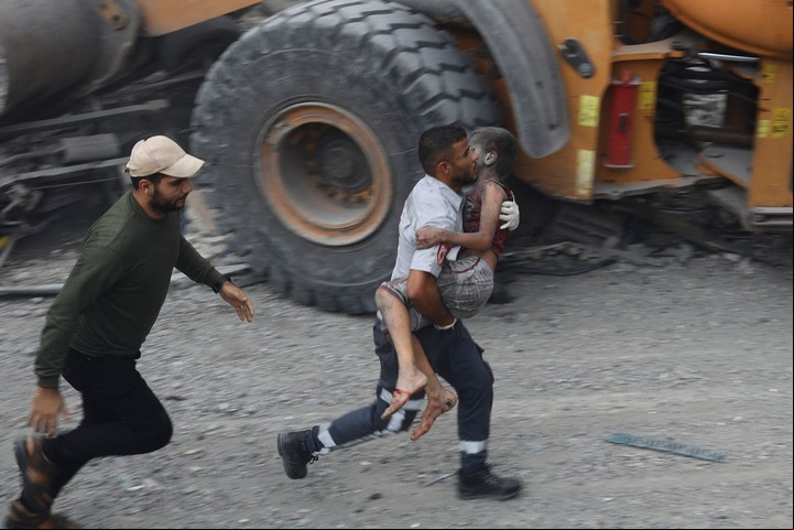 Un hombre carga a un menor palestino herido. Foto: EYAD BABA / AFP