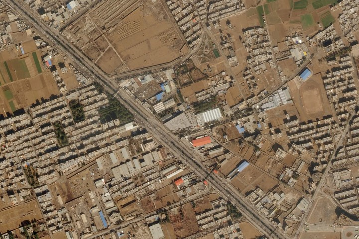 Una imagen aérea de grupos de edificios y campos marrones a ambos lados de una carretera en Isfahan, Irán, incluyendo los daños en el techo de un taller militar iraní, centro, después de un ataque con drones el 2 de febrero de 2023. Foto Planet Labs PBC